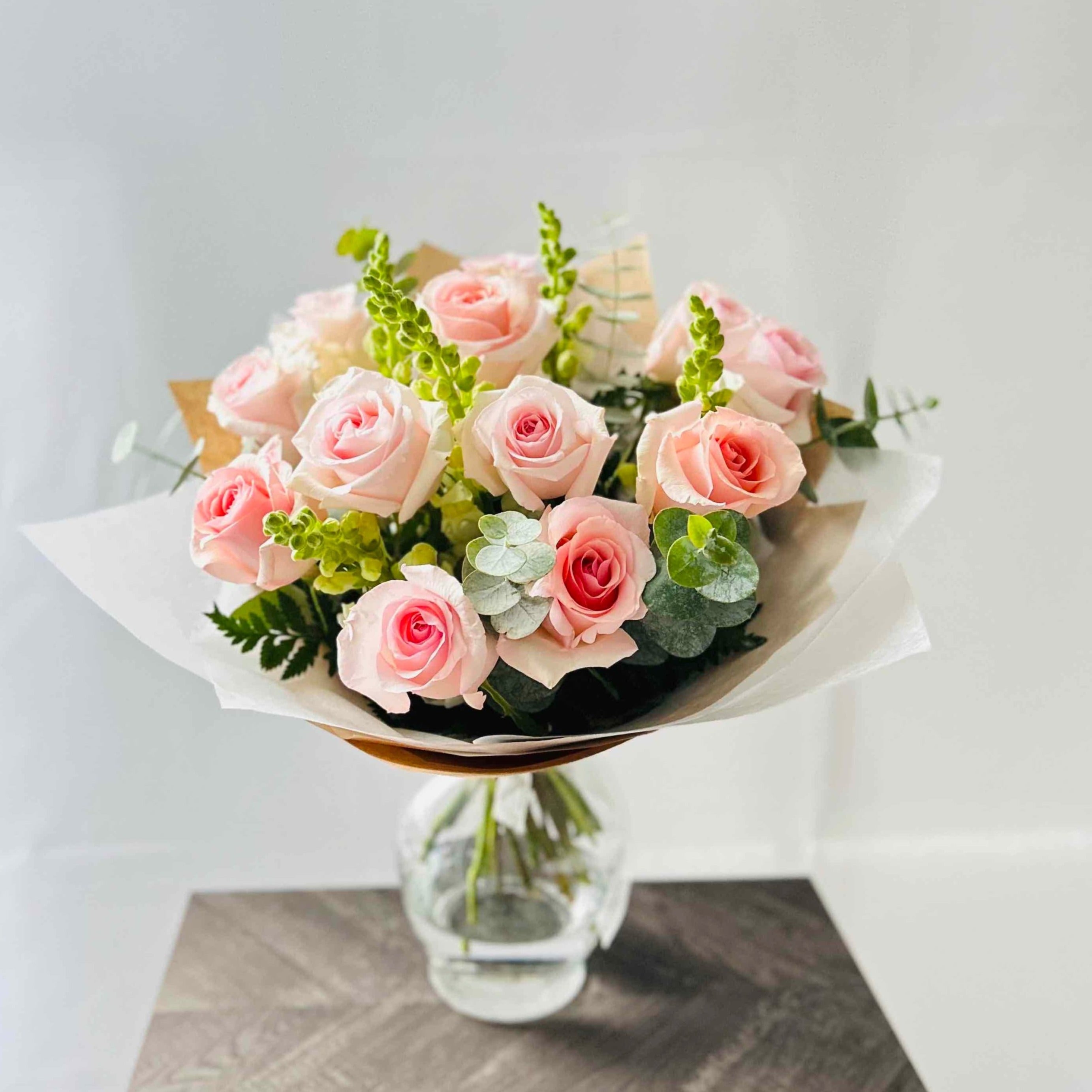 Beautiful pink roses, white snapdragons and eucalyptus bouquet in vase for home or office