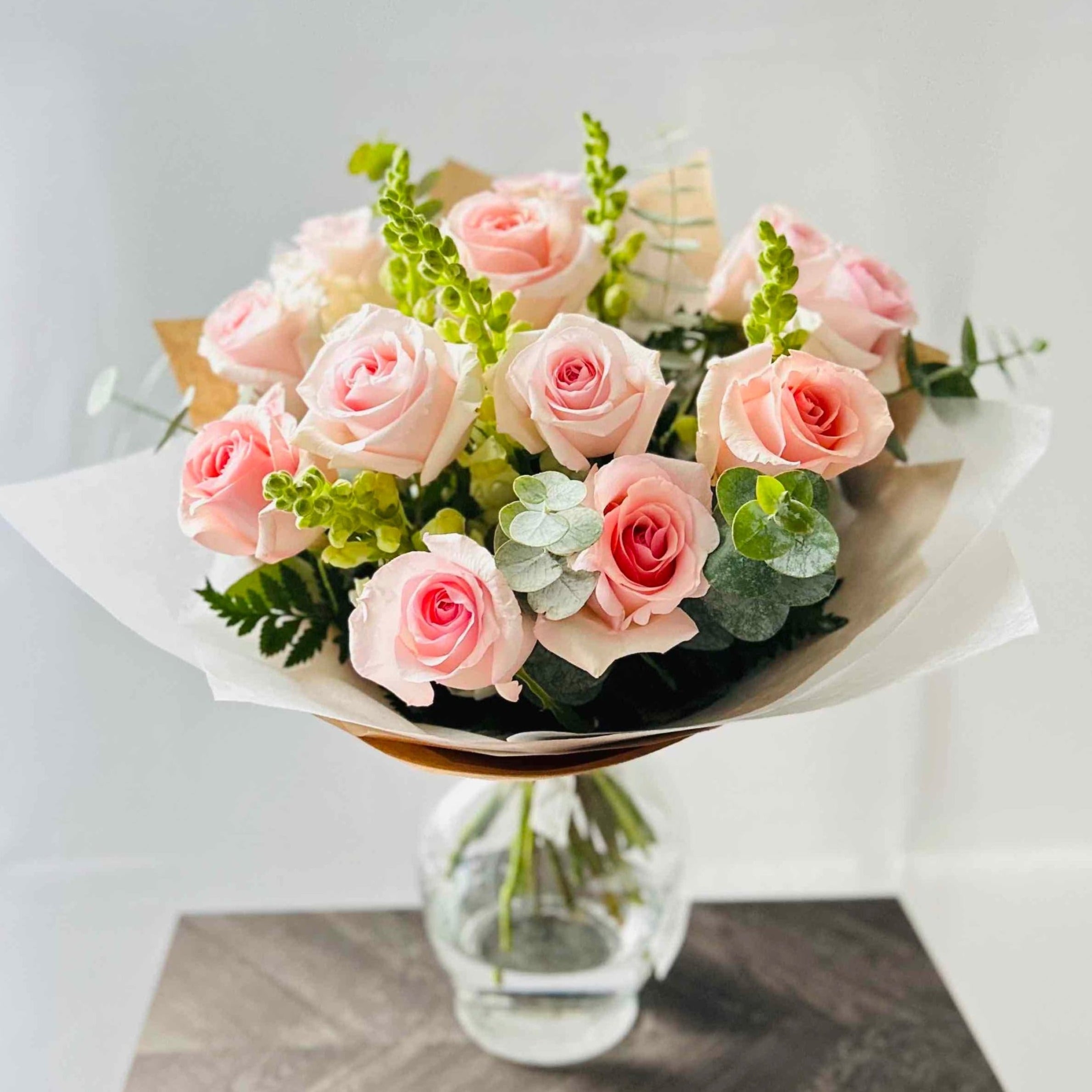Beautiful pink roses, white snapdragons and eucalyptus bouquet in vase for home or office