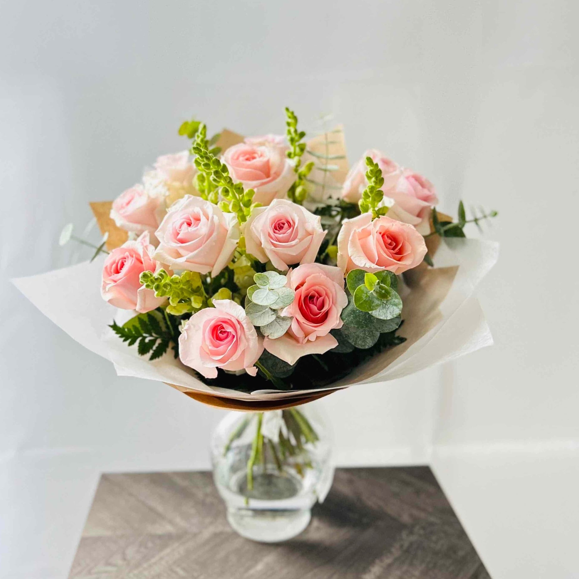 Beautiful pink roses, white snapdragons and eucalyptus bouquet in vase for home or office 