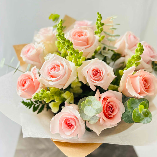A beautiful bouquet of pink roses, white snapdragons and eucalyptus, arranged in a clear vase, perfect for any occasion and as home or office decor